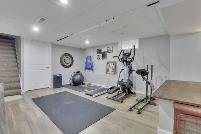 workout area with baseboards, visible vents, wood finished floors, and a paneled ceiling
