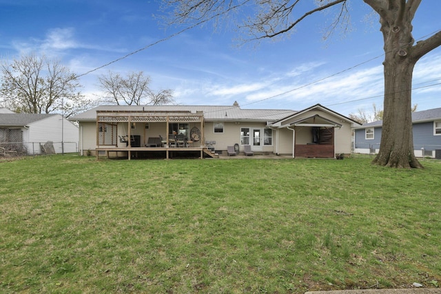 rear view of house with a wooden deck, a yard, and fence