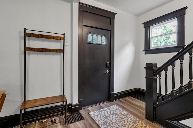 foyer entrance featuring stairway, baseboards, and wood finished floors
