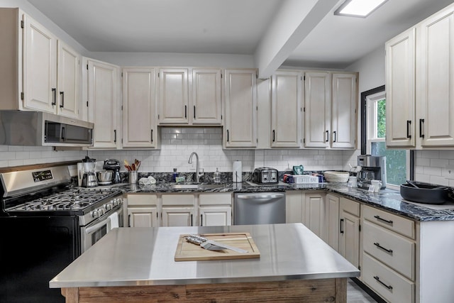 kitchen with a sink, decorative backsplash, appliances with stainless steel finishes, and dark stone countertops