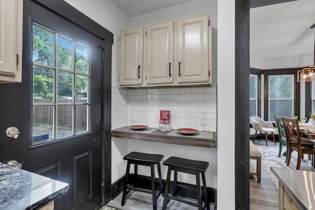 kitchen featuring dark countertops, a notable chandelier, decorative backsplash, and wood finished floors