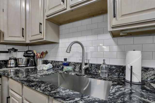 room details featuring a sink, dark stone counters, and backsplash