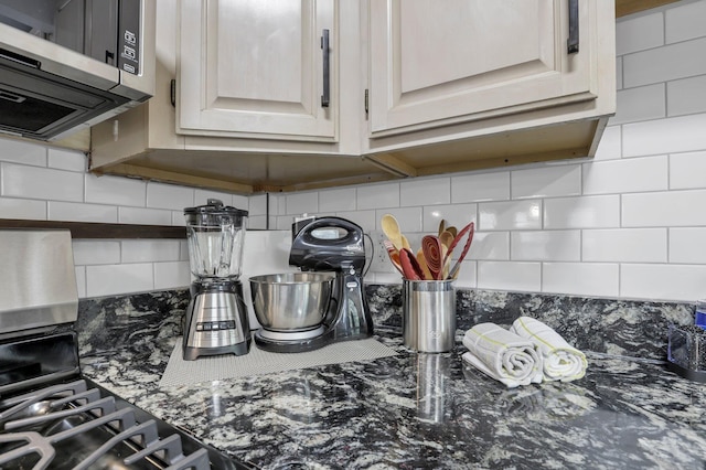 room details featuring dark stone counters, decorative backsplash, and stainless steel microwave