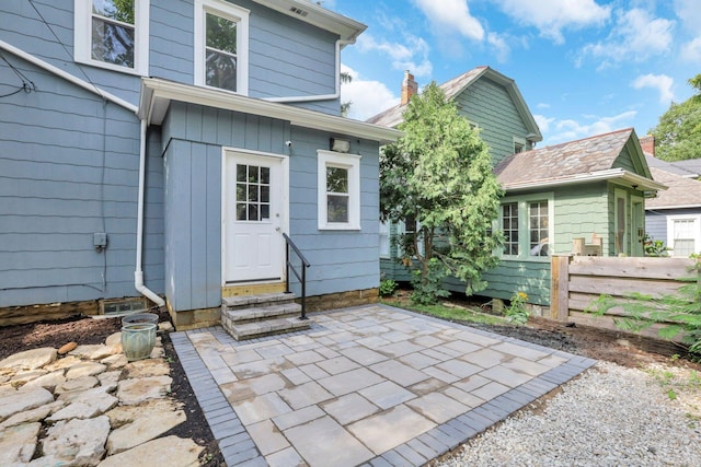 rear view of house featuring entry steps, fence, and a patio