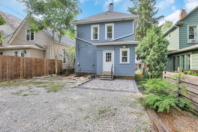 back of house featuring fence, a chimney, a shingled roof, a patio area, and entry steps