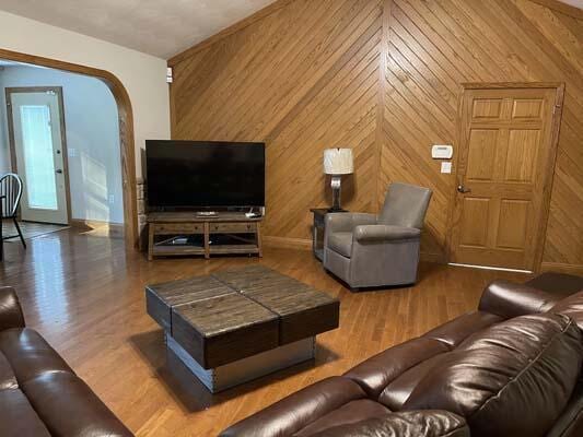 16900 Thompson Ridge Rd, Laurelville, OH 43135 - living room featuring wood walls, baseboards, arched walkways, and wood finished floors