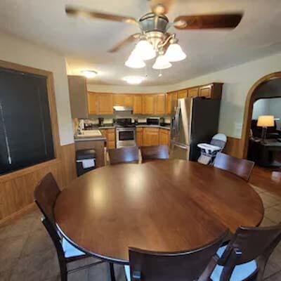 16900 Thompson Ridge Rd, Laurelville, OH 43135 - dining area featuring light tile patterned floors, a ceiling fan, a wainscoted wall, wood walls, and arched walkways