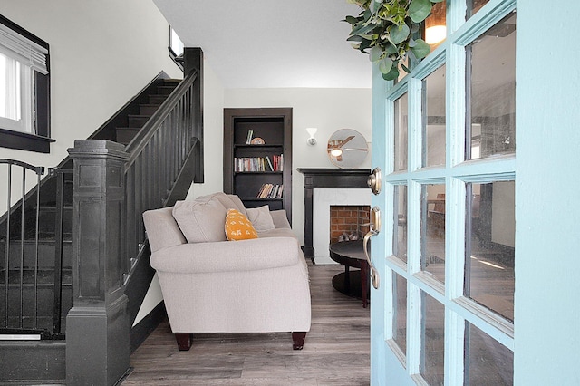 living area with stairs, wood finished floors, built in features, and a fireplace