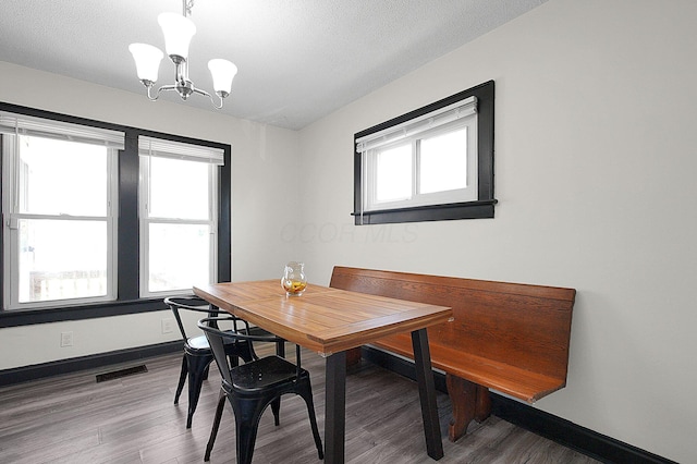 dining space featuring a notable chandelier, visible vents, baseboards, and wood finished floors