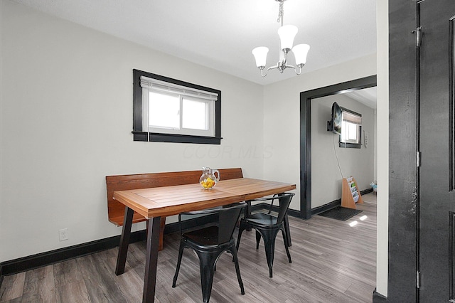 dining area with an inviting chandelier, light wood finished floors, and baseboards