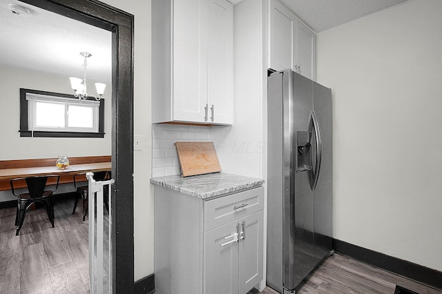 kitchen featuring stainless steel fridge, a chandelier, light wood-style flooring, white cabinetry, and decorative backsplash