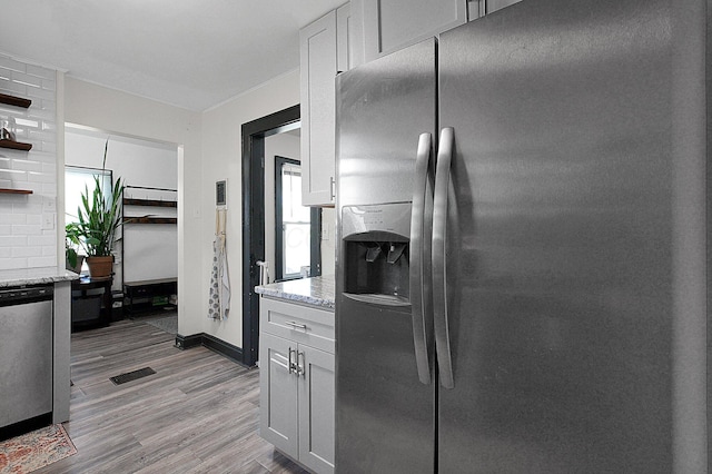 kitchen featuring open shelves, light stone countertops, baseboards, stainless steel fridge, and light wood-type flooring