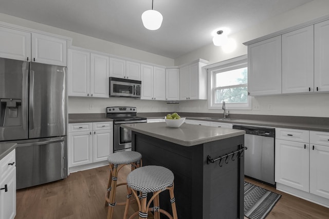 kitchen featuring a sink, dark countertops, white cabinets, dark wood-type flooring, and appliances with stainless steel finishes