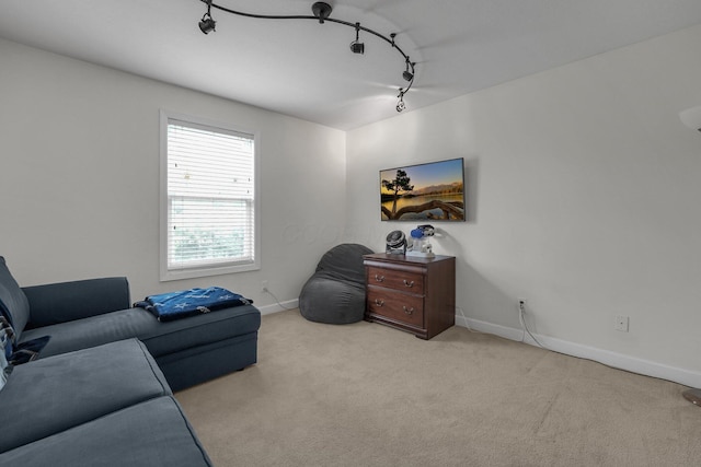carpeted living area featuring track lighting and baseboards