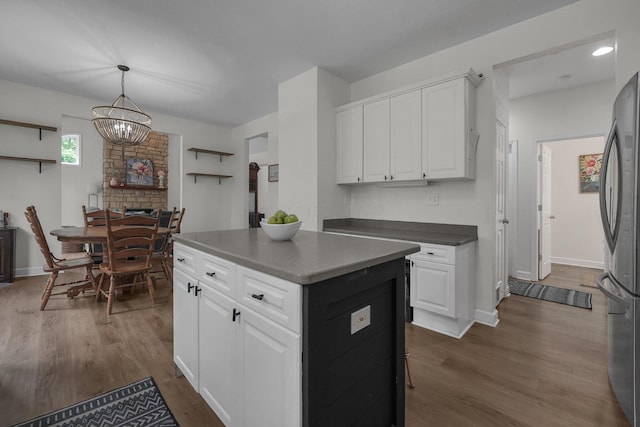 kitchen featuring freestanding refrigerator, a center island, white cabinetry, and dark wood-type flooring