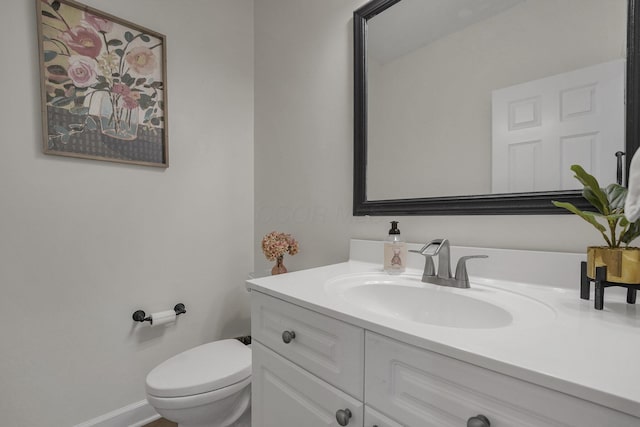 half bathroom featuring vanity, toilet, and baseboards