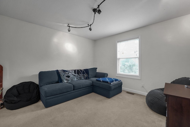 carpeted living area featuring rail lighting, baseboards, and visible vents