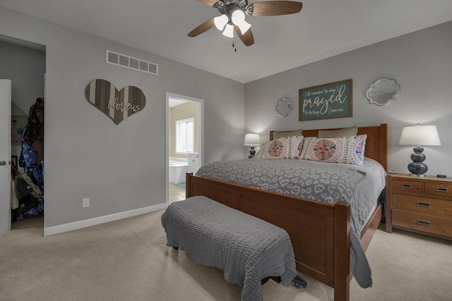 bedroom with baseboards, ensuite bath, visible vents, a walk in closet, and light colored carpet