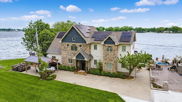 11290 Honeycreek Rd NW, Thornville, OH 43076 - view of front of house featuring stone siding, a front lawn, a water view, roof mounted solar panels, and a shingled roof