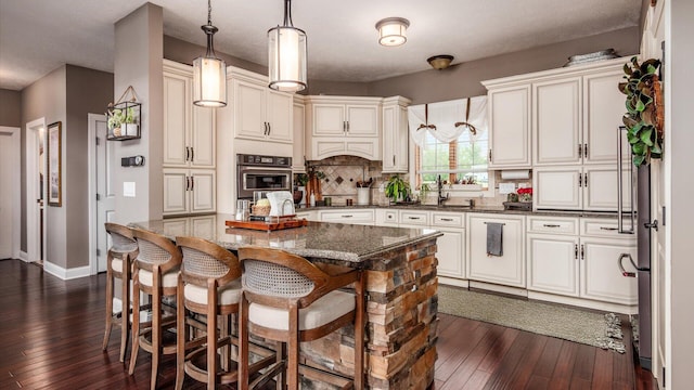 11290 Honeycreek Rd NW, Thornville, OH 43076 - kitchen with oven, dark wood-style floors, a kitchen breakfast bar, dark stone countertops, and decorative backsplash