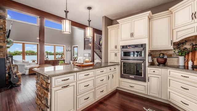 11290 Honeycreek Rd NW, Thornville, OH 43076 - kitchen with stainless steel double oven, cream cabinets, dark stone countertops, and dark wood finished floors