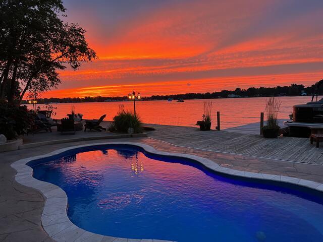 11290 Honeycreek Rd NW, Thornville, OH 43076 - pool at dusk featuring an outdoor pool, a water view, a patio, and a boat dock