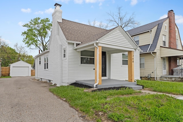 view of front of house with covered porch, a garage, a chimney, an outdoor structure, and roof with shingles