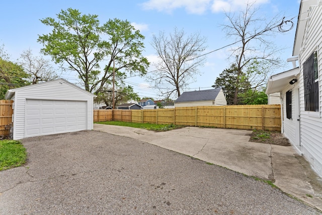 view of yard featuring an outbuilding, driveway, fence, and a detached garage