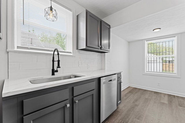 kitchen with a sink, wood finished floors, dishwasher, gray cabinetry, and baseboards