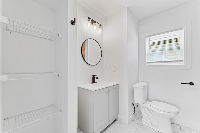 bathroom with vanity, toilet, baseboards, and marble finish floor