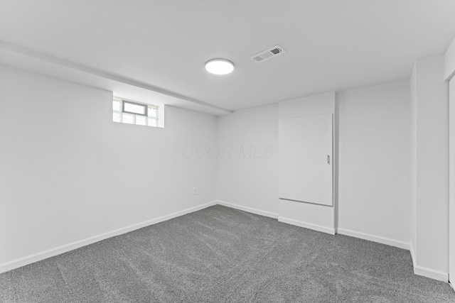 basement with baseboards, visible vents, and dark carpet
