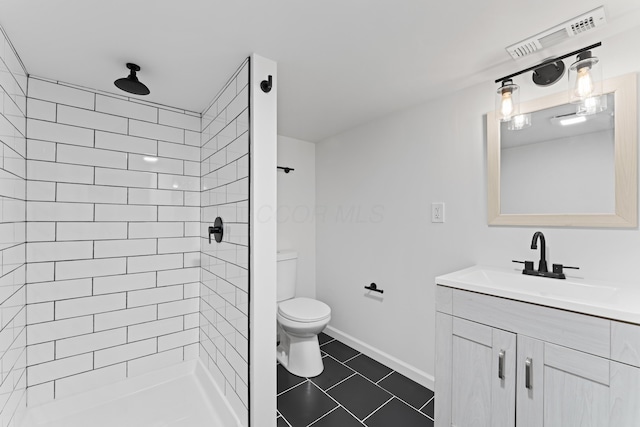 full bath featuring vanity, toilet, visible vents, and a tile shower
