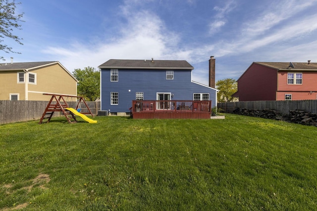 rear view of property featuring a lawn, a deck, central AC unit, a fenced backyard, and a playground