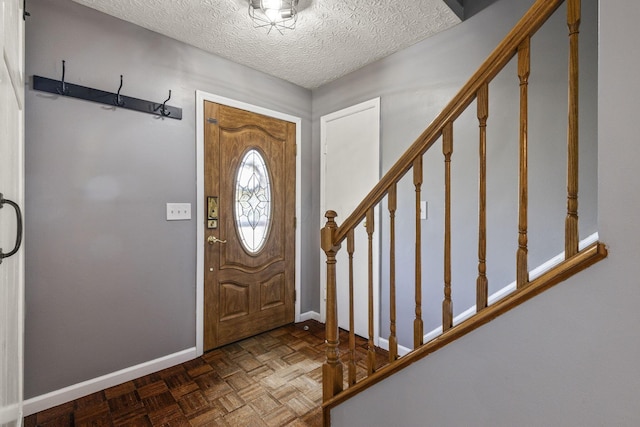 foyer entrance with baseboards, stairs, and a textured ceiling