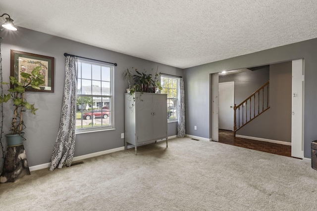 interior space with a textured ceiling, baseboards, and stairway