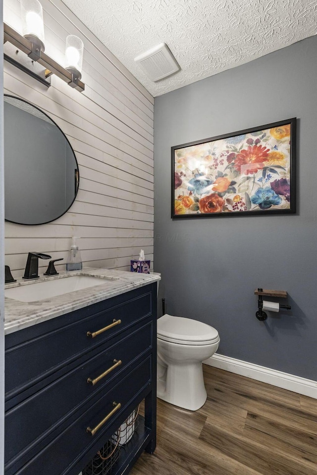 bathroom with visible vents, wood finished floors, vanity, toilet, and wooden walls