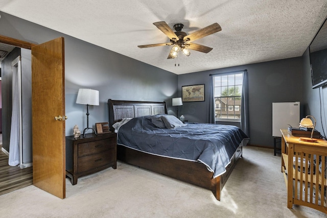 bedroom featuring light colored carpet, a textured ceiling, ceiling fan, and baseboards