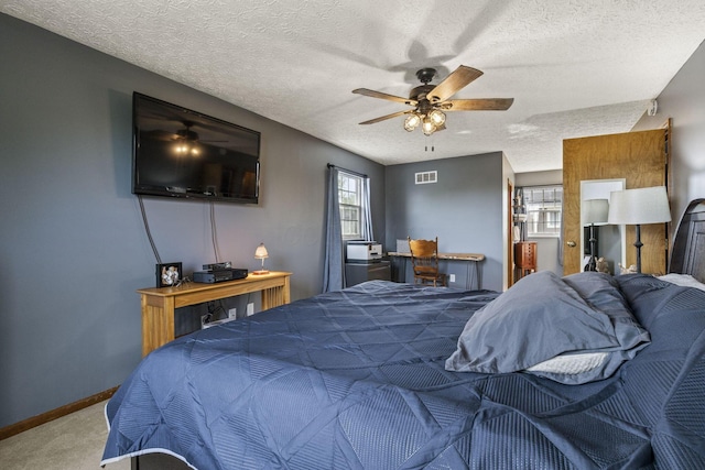 bedroom with a textured ceiling, visible vents, multiple windows, and carpet