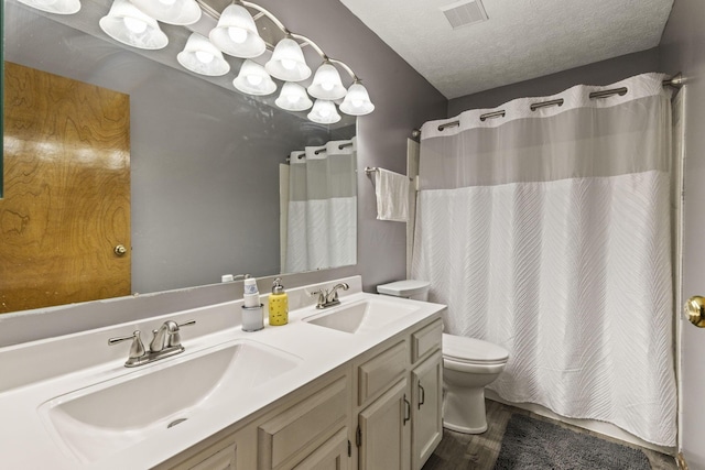 bathroom with double vanity, toilet, visible vents, and a sink