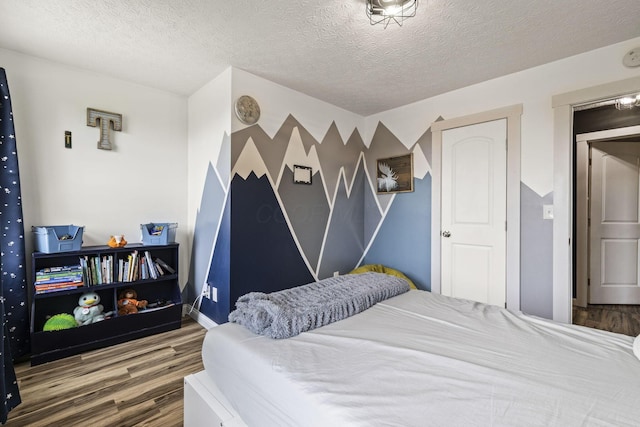 bedroom featuring a textured ceiling, baseboards, and wood finished floors
