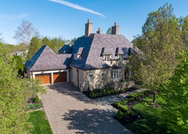 2528 Onandaga Dr, Upper Arlington, OH 43221 - view of front of property with a garage, a chimney, decorative driveway, stone siding, and a high end roof