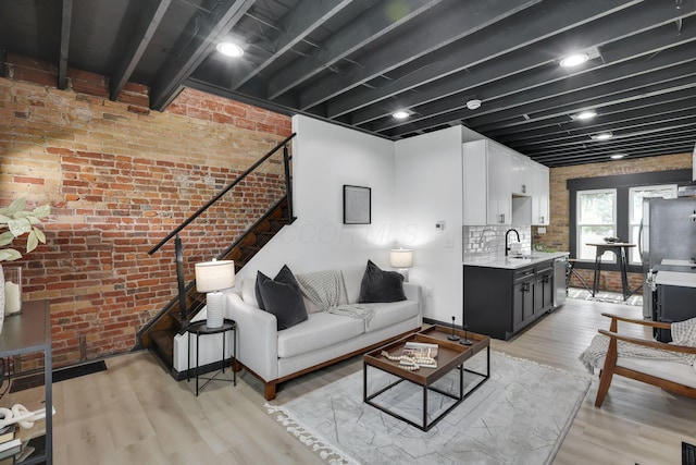 1010 Bruck St, Columbus, OH 43206 - living room featuring stairs, brick wall, and light wood-type flooring