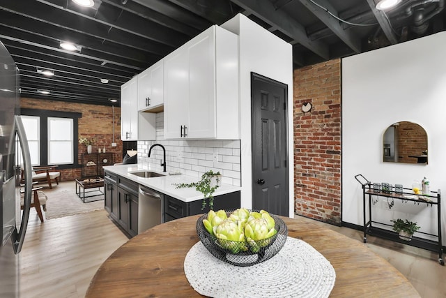 1010 Bruck St, Columbus, OH 43206 - kitchen with a sink, light wood finished floors, brick wall, and dishwasher