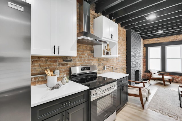 1010 Bruck St, Columbus, OH 43206 - kitchen featuring wall chimney range hood, appliances with stainless steel finishes, light countertops, brick wall, and light wood-style flooring