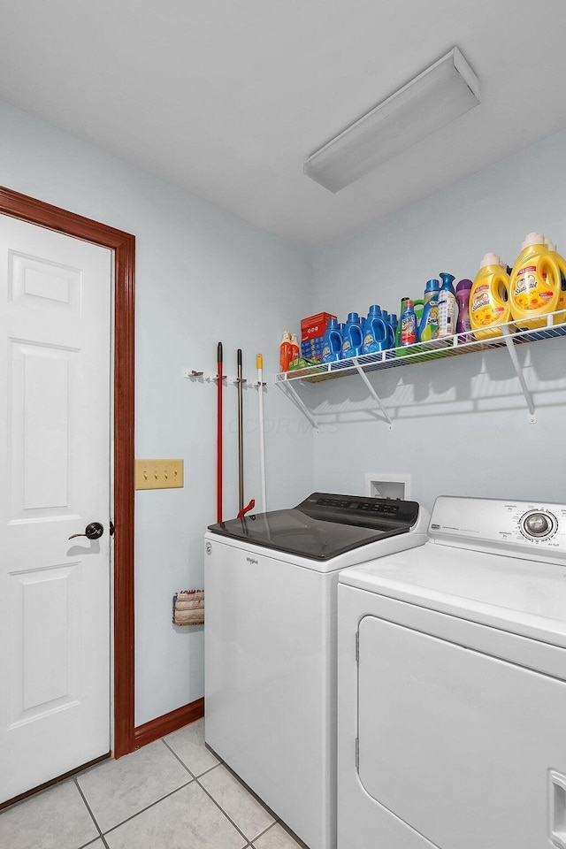 clothes washing area featuring washer and clothes dryer, laundry area, and light tile patterned flooring