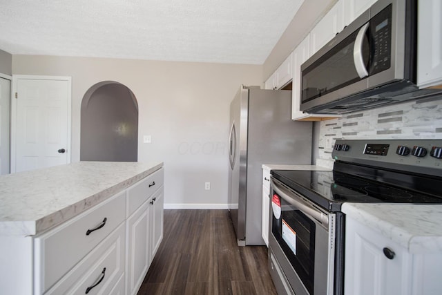 kitchen with backsplash, stainless steel appliances, white cabinets, and dark wood-style flooring