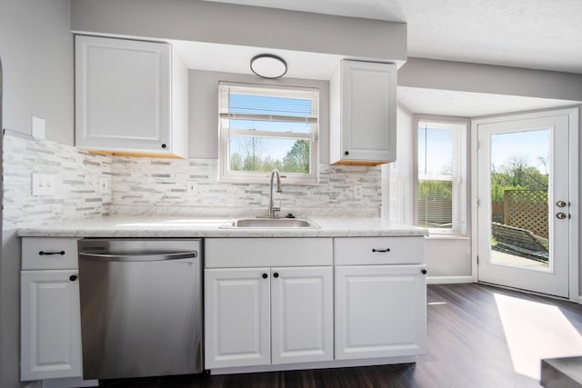 kitchen featuring white cabinets, a sink, backsplash, stainless steel dishwasher, and dark wood-style floors