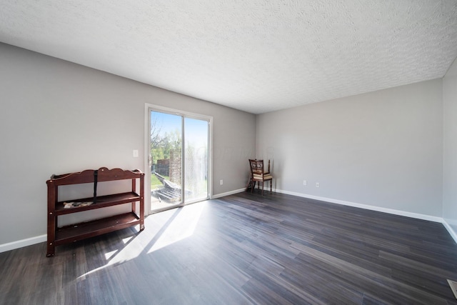 spare room with baseboards, a textured ceiling, and dark wood-type flooring