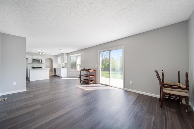 living room with baseboards, a textured ceiling, dark wood-style floors, and visible vents