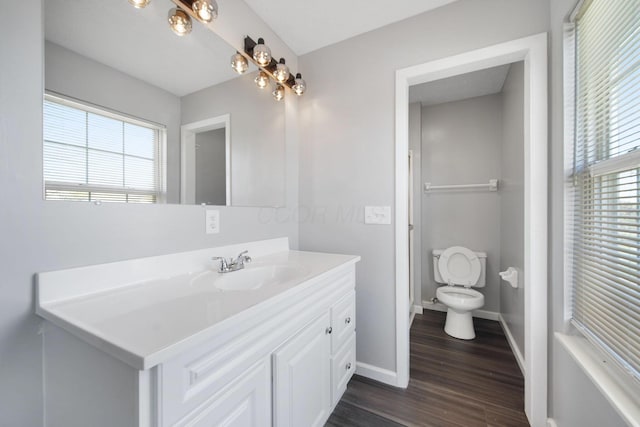 bathroom featuring baseboards, wood finished floors, toilet, and vanity